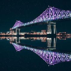 a bridge that is lit up in purple and blue at night with the lights on