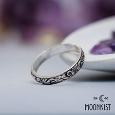 two wedding rings sitting next to each other on a white plate with purple flowers in the background