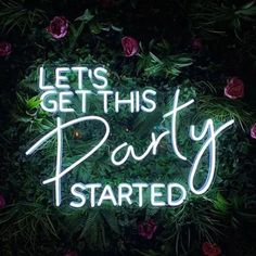 a neon sign that says let's get this party started in front of flowers