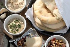 several bowls of food on a table with bread, dips and other foods in them