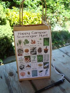 a happy camper scavenger hunt sign on a picnic table with trees in the background