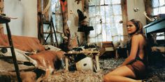 a woman sitting on the floor in front of a window with cow heads hanging from it's ceiling