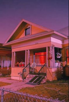 a small yellow house with red shutters on the front and side windows at night