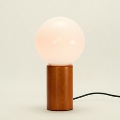 a wooden table lamp with a white ball on top and a black cord connected to it