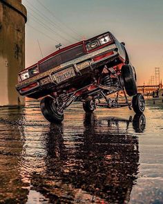 a red truck is parked in the middle of some water and people are walking around