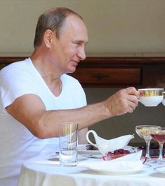 an older man sitting at a table with two glasses of wine