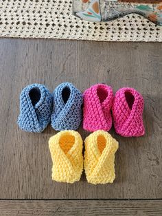 four crocheted baby booties sitting on top of a wooden floor next to each other