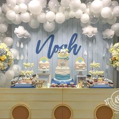 a table topped with a cake covered in white balloons next to a sign that says north