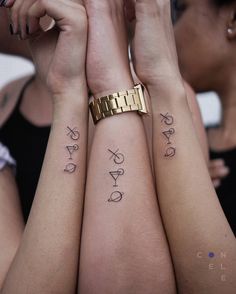 two women with matching tattoos on their arms holding hands in front of each other's faces