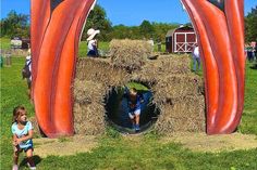 two children are playing in a giant sculpture made out of straw bales on the grass