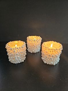 three candles are sitting on a black surface