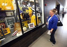 a woman is walking down the hallway in front of a store window with hockey memorabilia