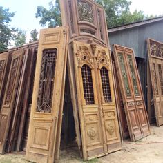 several large wooden doors are stacked up outside