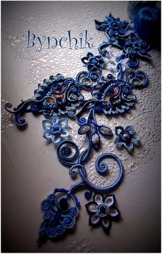 an intricate blue and white wall hanging on the side of a wall next to a vase with flowers