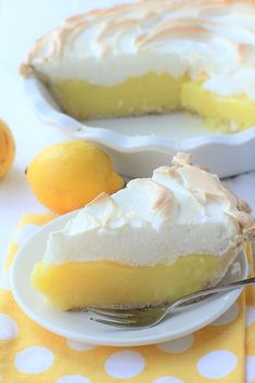 a slice of lemon meringue pie on a white plate with a yellow polka dot tablecloth