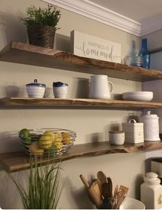 two wooden shelves with bowls, plates and utensils on them in a kitchen