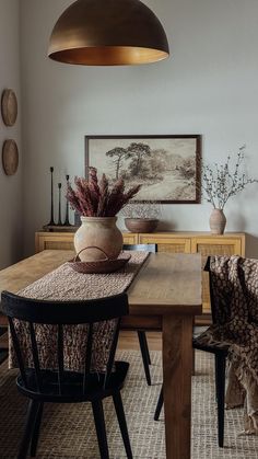 a dining room table with two chairs and a potted plant