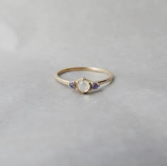 a gold ring with an opal and tan sapphire stones on the side, sitting on a white surface