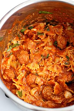 a large pot filled with pasta and meat in tomato sauce, garnished with parsley