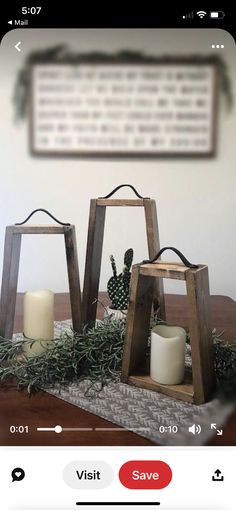 two small wooden lanterns sitting on top of a table next to candles and greenery