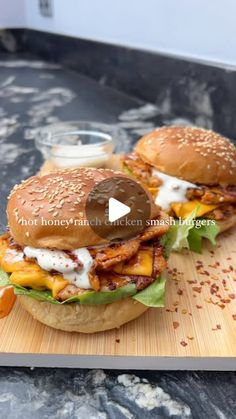 two hamburgers sitting on top of a wooden cutting board