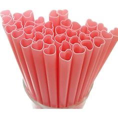 a glass vase filled with lots of pink heart shaped straws on top of a white table