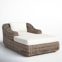 a wicker chaise lounge chair with white cushions