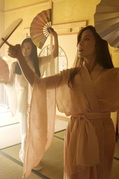 two women in kimonos holding parasols and standing on the floor next to each other