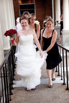 two brides are walking down the stairs with their bouquets in hand and one is wearing a black strapless dress