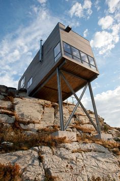 a tall wooden structure sitting on top of a rocky cliff under a blue cloudy sky