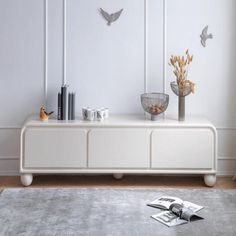 a living room with white furniture and birds on the wall above it's entertainment center