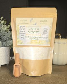 a bag of lemon burst next to a wooden spoon and potted plant on a table