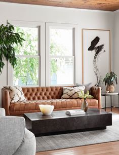 a living room with two couches and a coffee table in front of three windows