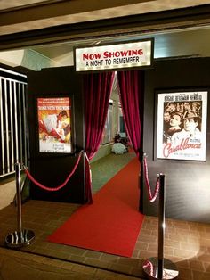 a red carpeted entrance to a movie theater with posters on the wall behind it