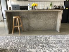 a kitchen with a bar and stools in the middle, next to a rug on the floor