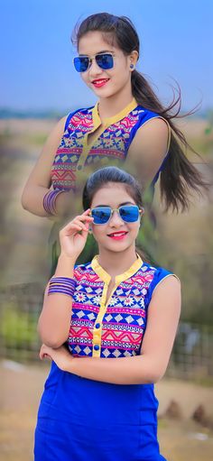 a woman wearing sunglasses and a blue dress posing for the camera with her hair blowing in the wind