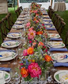 a long table is set with plates and place settings for an outdoor dinner or party