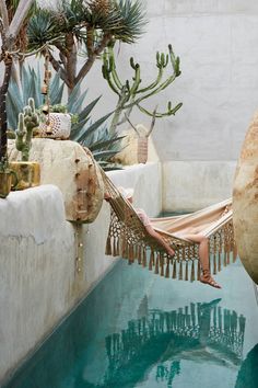 a woman laying in a hammock on top of a pool next to plants