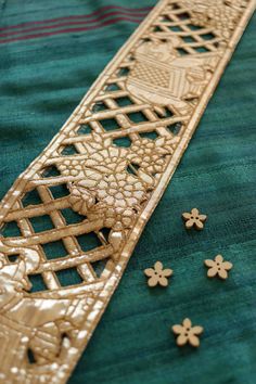 an intricately designed piece of cloth with flowers and leaves on the edge, sitting on a green tablecloth