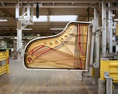 a grand piano hanging from the ceiling in a building with wooden floors and yellow railings