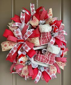 a red and white christmas wreath hanging on the front door with snowflakes, mitts and ribbons