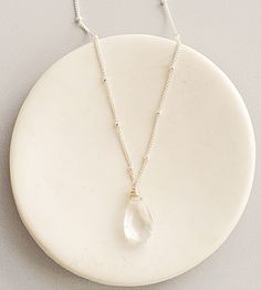 A dazzling accent for the neckline, this rock quartz drop pendant is must have. This faceted gemstone floats over delicately beaded chain adding a dainty touch.    The lobster clasp and link closure are adorned with tiny beads that add another touch of femininity.  This timeless pendant is now available in your choice of sterling silver or 14kt gold fill. Elegant Herkimer Diamond Crystal Necklace Gift, Elegant Herkimer Diamond Crystal Necklaces For Gifts, Silver Faceted Crystal Necklace For Healing, Silver Faceted Crystal Necklaces For Healing, Wire Wrapped Crystal Necklace In Sterling Silver, Sterling Silver Crystal Necklace With Faceted Beads For Gift, Faceted Silver Crystal Necklace For Spiritual Use, Gift Herkimer Diamond Necklace In Silver, Clear Quartz Crystal Necklace With Gemstone