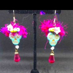 two pairs of earrings with pink and blue flowers on them are hanging from a black stand