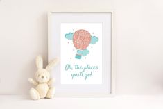 a stuffed rabbit sitting next to a framed print with the words oh, the places you'll go