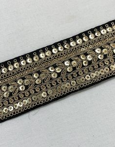 a black and gold belt with lots of buttons on it's side, sitting on a white surface