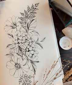 a black and white drawing of flowers on a piece of paper next to a candle