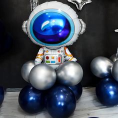 an astronaut balloon sitting on top of blue and silver balloons