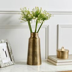 a gold vase with flowers in it sitting on a table next to a framed photograph