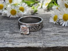 a close up of a ring on a wooden surface with daisies in the background