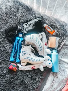 an assortment of sports equipment is laid out on a blanket, including shoes and water bottles